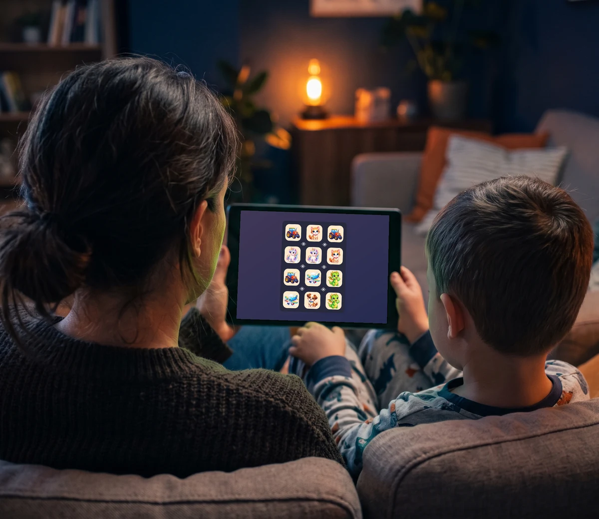 Szülő és gyerek hátulról a kanapén, közösen játszanak a Kids mód figurás pályájával a tableten